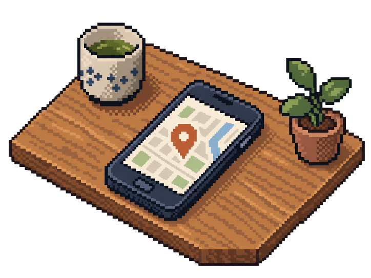 木の机に置かれたスマートフォン（地図アプリ）と湯呑み、観葉植物